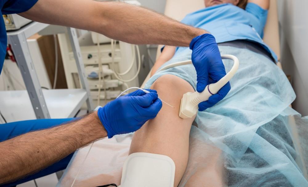 A high-definition image of a healthcare professional treating a patient's leg ulcer in a clinical setting.